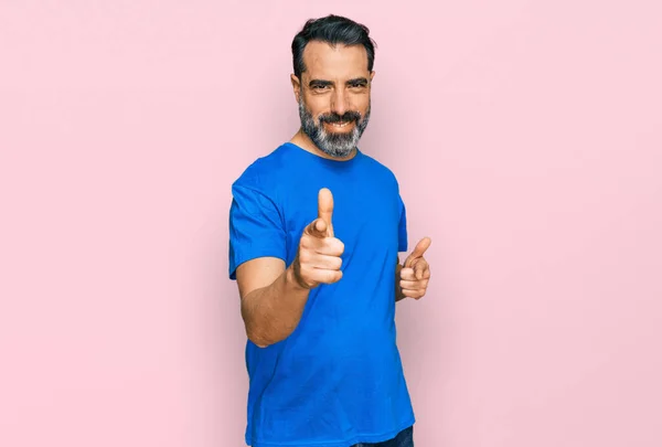 髭を生やした中年男性が 楽しそうな顔をしてカメラに指を指すカジュアルな青のTシャツを着ていた 良いエネルギーと振動は — ストック写真