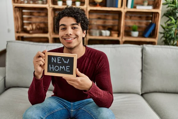 Jovem Hispânico Sorrindo Feliz Segurando Novo Quadro Negro Casa Sentado — Fotografia de Stock