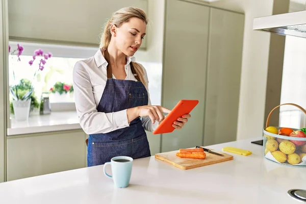 Genç sarışın kadın mutfakta dokunmatik ped kullanıyor.