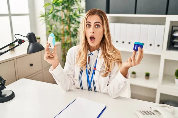 Young Blonde Doctor Woman Holding Medicine Products Breath Better Afraid — Foto de Stock