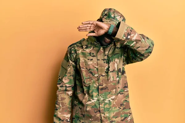 Afrika kökenli genç bir Amerikalı asker üniforması giyiyor. Gözleri, kollarıyla gülüyor. Neşeli ve komik. kör kavram. 
