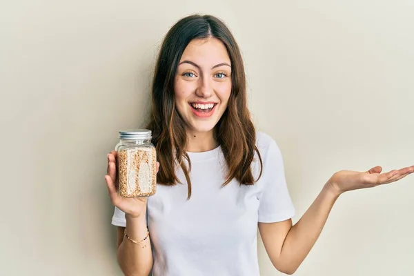 Young Brunette Woman Holding Jar Rice Celebrating Achievement Happy Smile — стоковое фото
