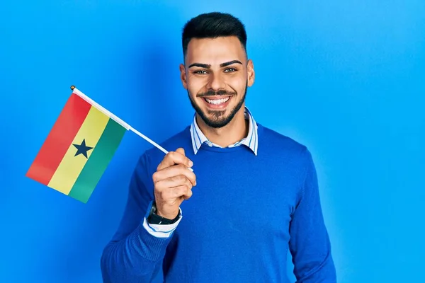 Young Hispanic Man Beard Holding Ghana Flag Looking Positive Happy —  Fotos de Stock
