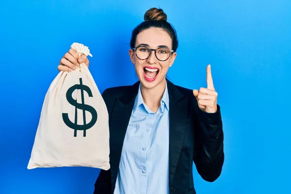 Young Hispanic Girl Wearing Business Clothes Holding Dollars Bag Smiling — 스톡 사진