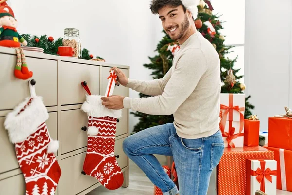 Jovem Hispânico Sorrindo Feliz Vestindo Chapéu Natal Segurando Presente Casa — Fotografia de Stock