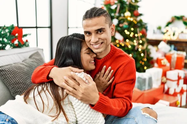 Young Latin Couple Smiling Happy Hugging Sitting Sofa Christmas Tree — Zdjęcie stockowe
