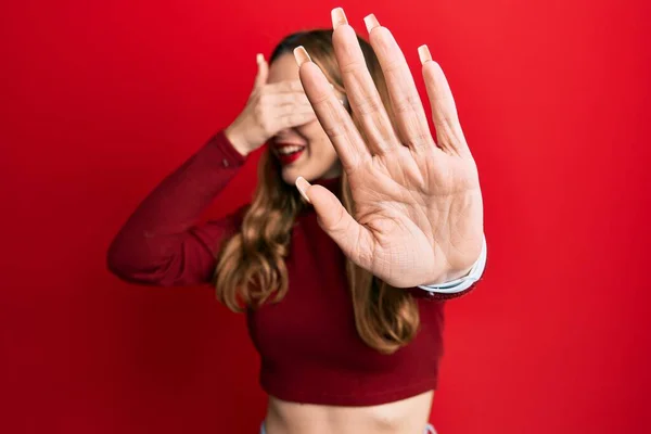 Young blonde woman wearing turtleneck sweater covering eyes with hands and doing stop gesture with sad and fear expression. embarrassed and negative concept.