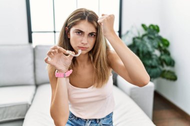 Genç sarışın kadın, görünmeyen hizalayıcı ortodontik kızgın ve kızgın. Öfkeyle bağırırken yumruğunu kaldırıyor. öfke ve agresif konsept. 