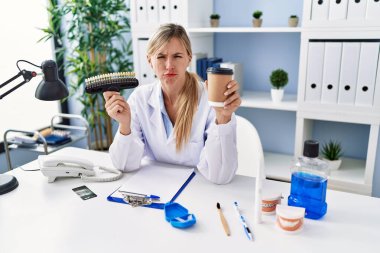 Diş fırçası takan güzel dişçi kadın şüpheci ve gergin, sorun yüzünden surat asıyor. negatif kişi. 