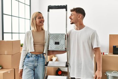 Yeni evimizde işçi merdivenleri tutarken mutlu gülümseyen beyaz bir çift..