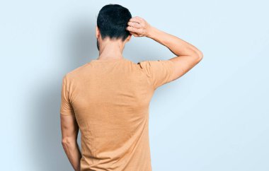 Sakallı, sıradan tişörtünü ters giymiş İspanyol bir adam. Elleri kafasında şüpheyi düşünüyor. 