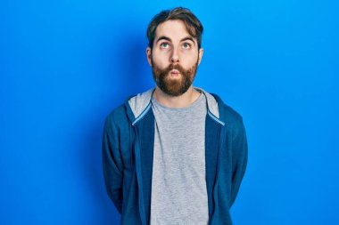 Sakallı, sıradan bir kazak giyen, dudağıyla balık suratı yapan, çılgın ve komik hareketler yapan beyaz bir adam. Komik ifade. 