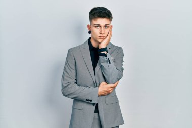 Kulakları genişlemiş, iş ceketi giymiş, depresyondan sıkılmış, kolları çaprazlanmış, yorgun görünen beyaz bir çocuk.. 