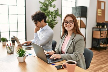 Ofiste dizüstü bilgisayarla çalışırken gülümseyen iki iş adamı..