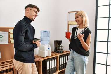 İki iş adamı gülümsüyor, ofiste kahve içiyorlar..