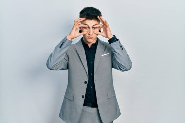 Young caucasian boy with ears dilation wearing business jacket trying to open eyes with fingers, sleepy and tired for morning fatigue 