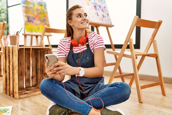 若い女性は自信を持って笑顔でスマートフォンを使ってアートスタジオ — ストック写真