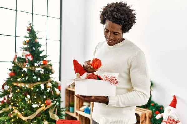 Young african american man smiling happy decorating christmas tree at home.