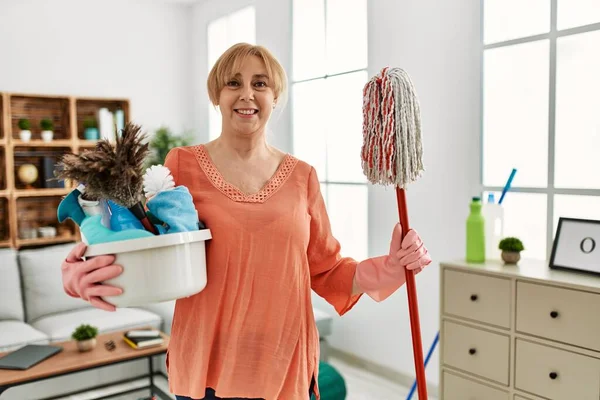 Medelålders Kvinna Ler Glad Innehav Rengöringsmedel Stående Hemma — Stockfoto