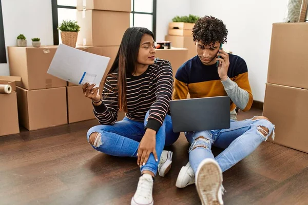 Young Latin Couple Using Laptop Talking Smartphone Sitting Floor New — Stock Fotó