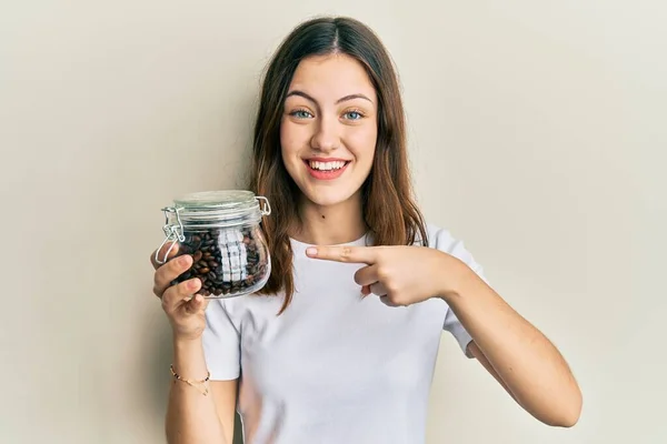 Young Brunette Woman Holding Jar Coffee Beans Smiling Happy Pointing — Stok fotoğraf