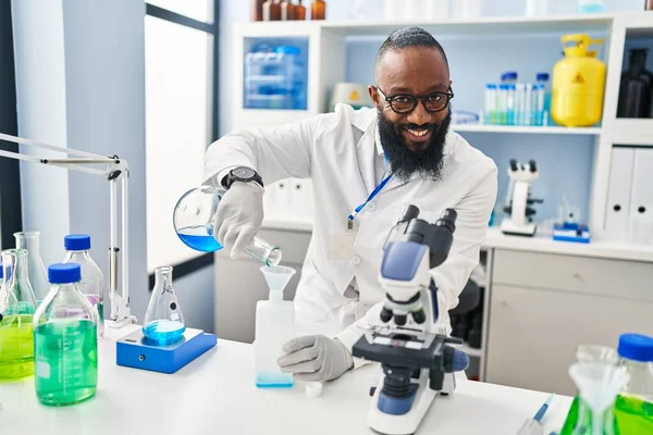 Young African American Man Wearing Scientist Uniform Measuring Liquid Laboratory — ストック写真