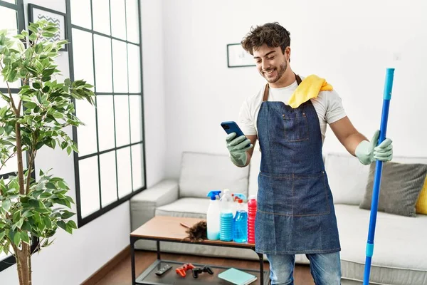 Νεαρός Ισπανόφωνος Άνδρας Χαμογελά Αυτοπεποίθηση Καθαρισμού Και Χρήση Smartphone Στο — Φωτογραφία Αρχείου