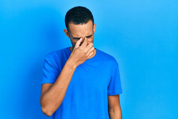 身穿休闲蓝T恤的年轻的非洲裔美国人疲倦地揉揉鼻子和眼睛 感到疲劳和头痛 压力和挫败感概念 — 图库照片