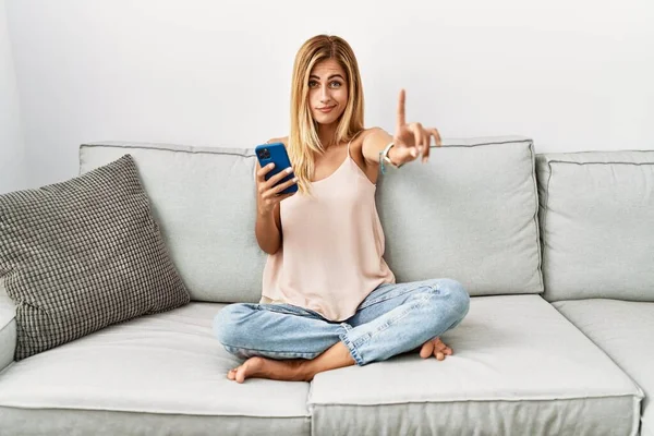 Blondýny Krásná Mladá Žena Sedí Pohovce Doma Pomocí Smartphone Ukazuje — Stock fotografie