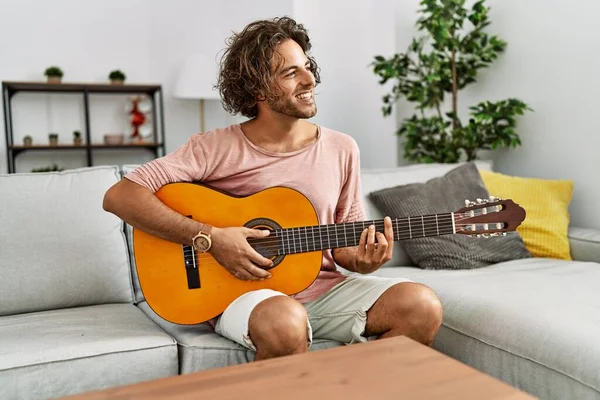 Ung Latinamerikansk Man Ler Glad Spelar Klassisk Gitarr Sitter Soffan — Stockfoto