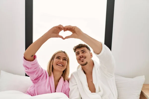 Young Caucasian Couple Smiling Happy Making Heart Symbol Hands Bed — Stockfoto