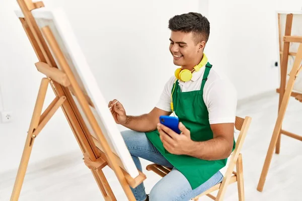 年轻的惊慌失措的男人在艺术工作室用智能手机画出自信的笑容 — 图库照片