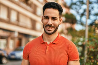 Genç İspanyol adam gülümseyerek şehirde mutlu mesut dikiliyor..