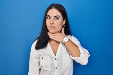 Mavi arka planda dikilen genç İspanyol kadın bıçakla boğazını kesiyor, saldırganlığı şiddetle tehdit ediyor. 