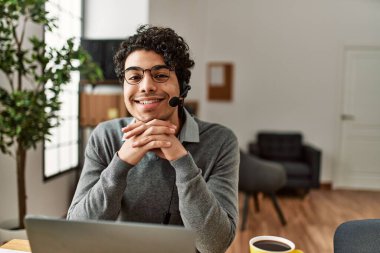 Ofiste çalışırken gülümseyen İspanyol bir çağrı merkezi ajanı..