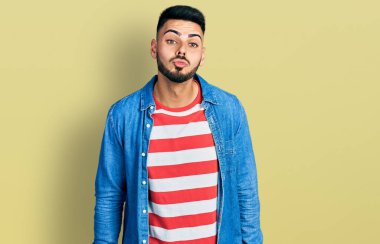 Sakallı, sıradan bir kot ceket giyen genç İspanyol bir adam havada öpücük yollayan kameraya bakıyor. Güzel ve seksi. aşk ifadesi. 