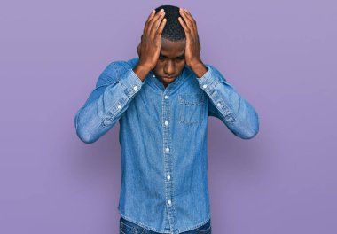 Genç Afro-Amerikan adam gündelik kıyafetler giyiyor. Baş ağrısı çekiyor, çaresiz ve stresli. Çünkü acı ve migren ağrısı var. Eller başının üstünde.. 