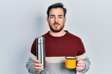 Sakallı, bir fincan kahve içen yakışıklı beyaz adam yüzünde ciddi bir ifadeyle termodinamik tutuyordu. Basit ve doğal bir şekilde kameraya bakıyorsun.. 