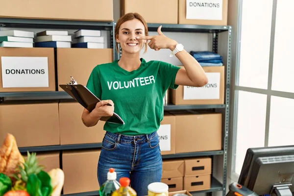 Bağışta gönüllü tişört giyen genç esmer kadın el ve yüz yüze, neşeli bir şekilde gülümsüyor. güzellik konsepti 