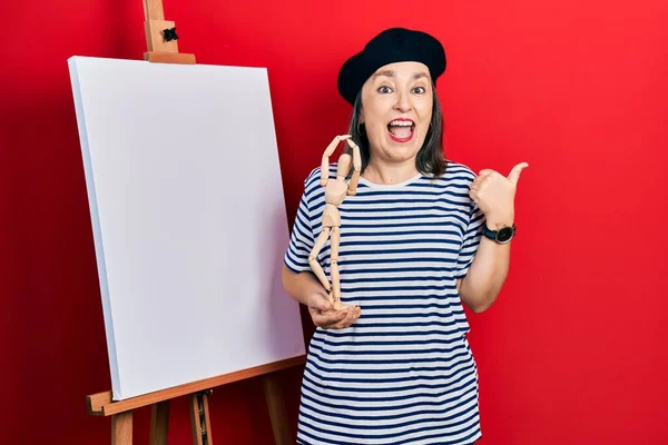 Middle Age Hispanic Woman Standing Painter Easel Stand Holding Manikin — Stock Photo, Image