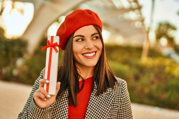 Νεαρή Ισπανίδα Γυναίκα Χαμογελά Χαρούμενη Κρατώντας Δώρο Στην Πόλη — Φωτογραφία Αρχείου