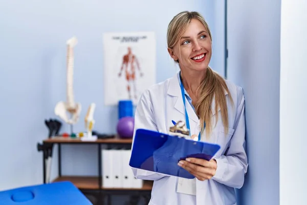 Jonge Blonde Vrouw Draagt Fysiotherapeut Uniform Schrijven Checklist Fysiotherapie Kliniek — Stockfoto