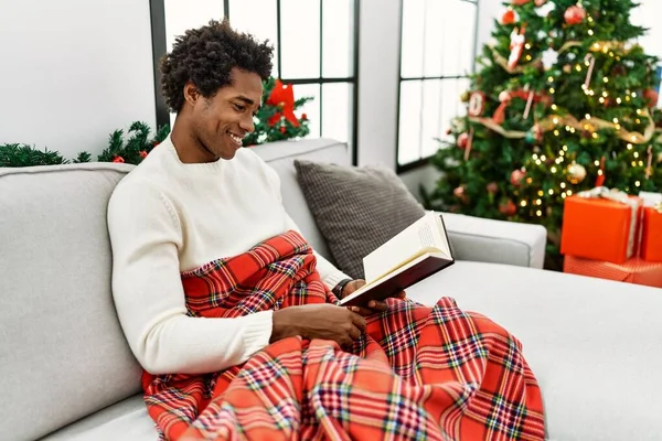 Young African American Man Reading Book Sitting Sofa Christmas Tree — Stock Photo, Image
