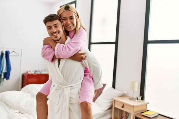 Mand carrying woman on his back standing at bedroom.