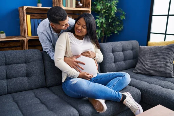 Young Latin Couple Expecting Baby Hugging Each Other Sitting Sofa — Foto de Stock