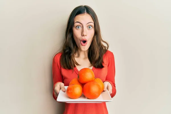 Young Brunette Woman Holding Plate Fresh Oranges Afraid Shocked Surprise — Foto Stock