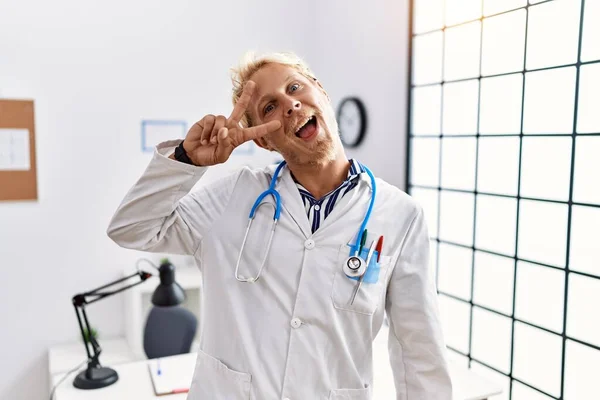 Joven Hombre Rubio Vistiendo Uniforme Médico Estetoscopio Clínica Haciendo Símbolo — Foto de Stock