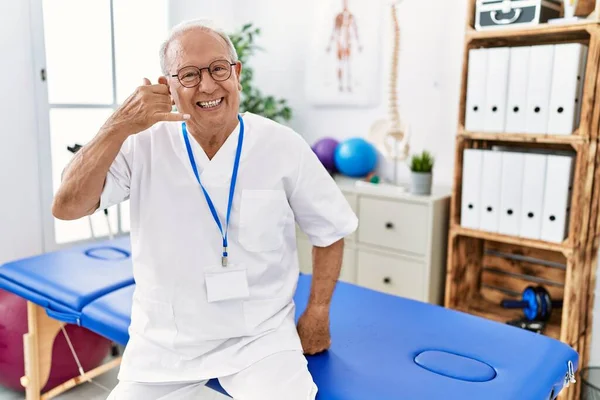 Ağrı Kesici Kliniğinde Çalışan Kıdemli Fizyoterapist Gülümsüyor Parmaklarıyla Telefonla Konuşuyor — Stok fotoğraf