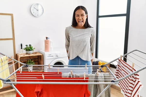 Mujer Hispana Joven Poniendo Ropa Fresca Tendedero Sacando Lengua Feliz —  Fotos de Stock