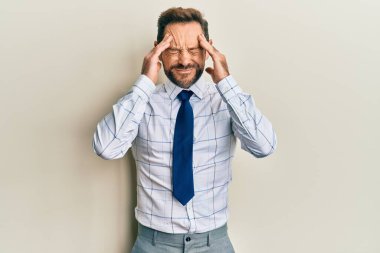 Orta yaşlı iş adamı iş gömleği giyiyor ve elleri kafasında kravat takıyor. Stres yüzünden baş ağrısı çekiyor. migren ağrısı. 